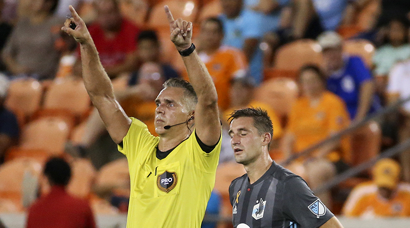 Tim Ford announces a video review after an initial goal by Minnesota United midfielder Ethan Finlay (13) during the second half against the Houston Dynamo at BBVA Compass Stadium.