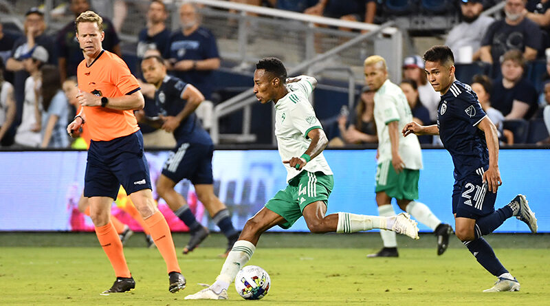 Mark Anthony Kaye #14 of Colorado Rapids with the ball during a game between Colorado Rapids and Sporting Kansas City at Children's Mercy Park on May 18, 2022 in Kansas City, Kansas, watched by referee Drew Fischer. Bill Barrett/ISI Photos.